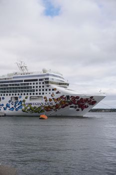 The Norwegian Gem cruise ship sails peacefully on the ocean, under a cloudy sky.
