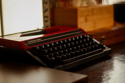 A nostalgic red typewriter sits elegantly on a wooden desk in a cafe, creating a vintage ambiance.