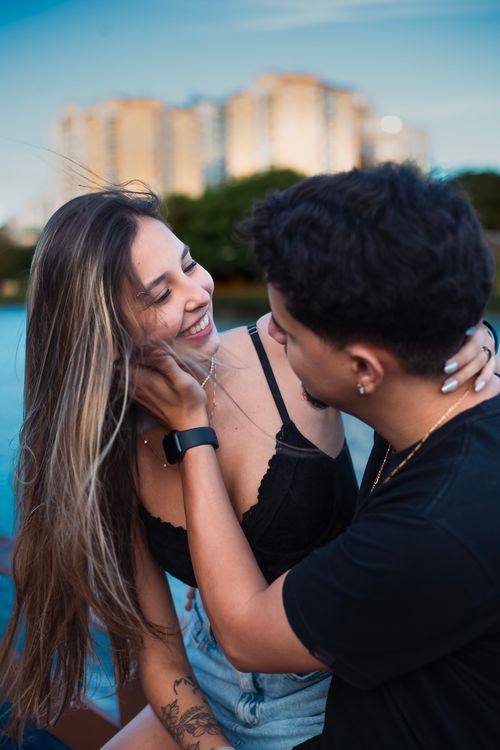 Free Happy young couple embracing by the water with city skyline in the background. Stock Photo