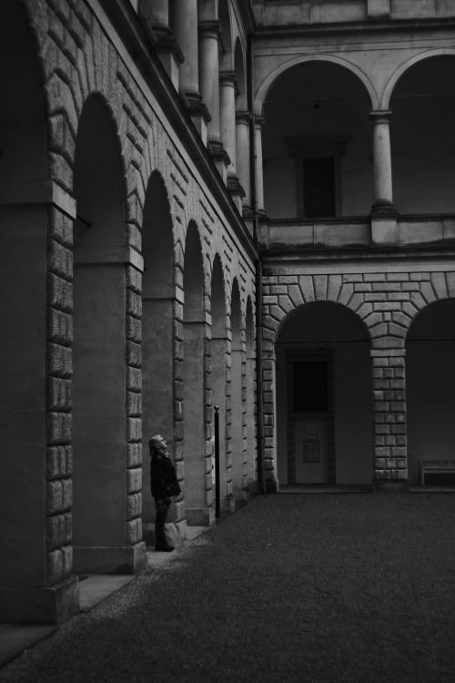 Free A serene moment in a historic courtyard with stone arches and columns in monochrome. Stock Photo