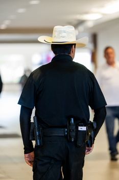 Photo by Caleb Oquendo Security guard with cowboy hat patrolling inside a building, showcasing law enforcement and security themes.