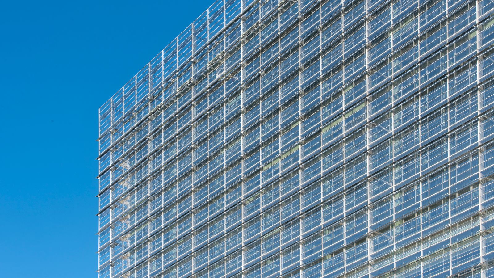 Glass facade of a modern building under clear blue sky in Rijswijk, Netherlands.