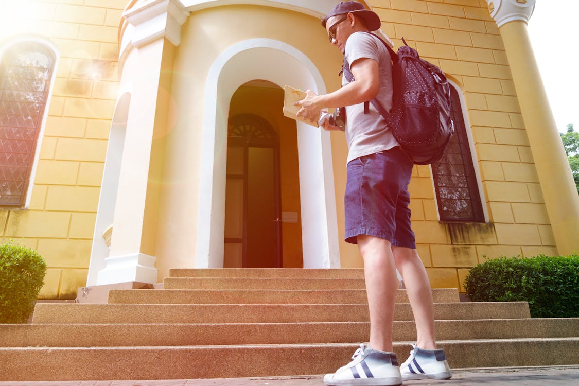 Free Man Standing and Facing in Front of a Beige House Stock Photo