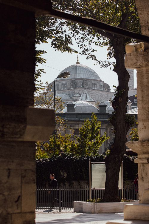 Free A historic mosque dome seen through ancient stone arches framed by trees in Istanbul. Stock Photo