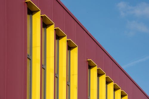 Free Colorful modern building facade with red and yellow panels under a clear blue sky. Stock Photo