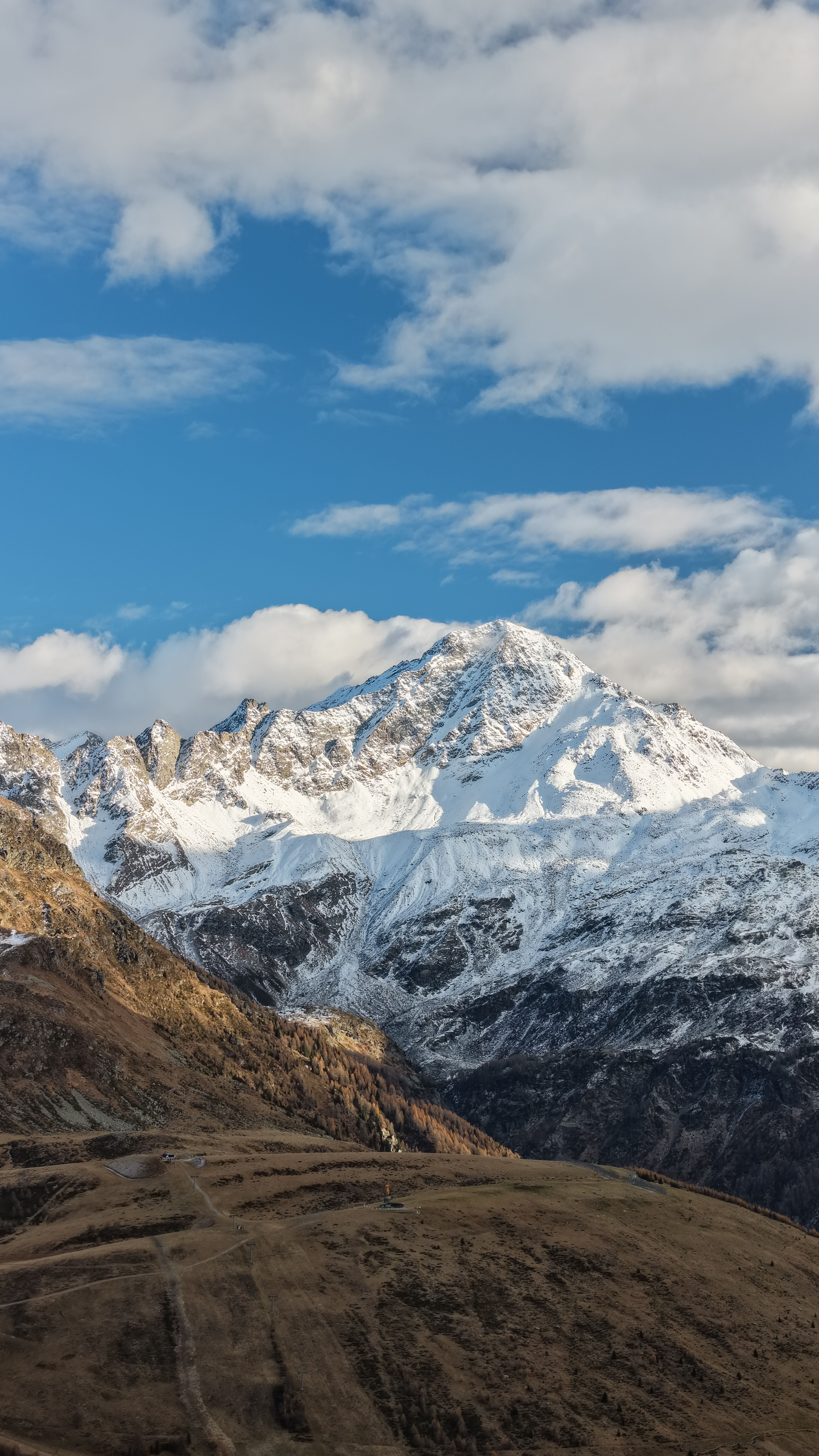 Majestic view of snow-capped Alps under a bright blue sky in Madesimo, Italy.