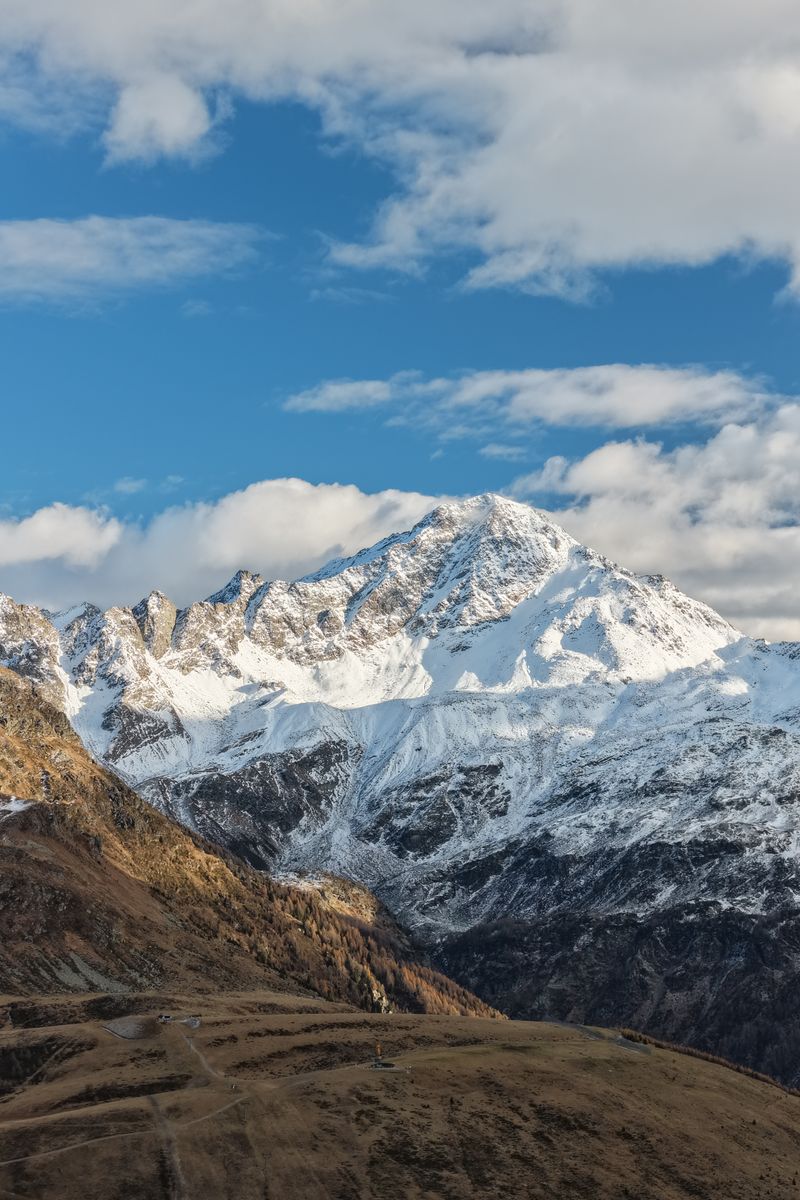 Majestic view of snow-capped Alps under a bright blue sky in Madesimo, Italy.