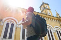 背包客在阳光下凝视着一座历史悠久的黄色教堂