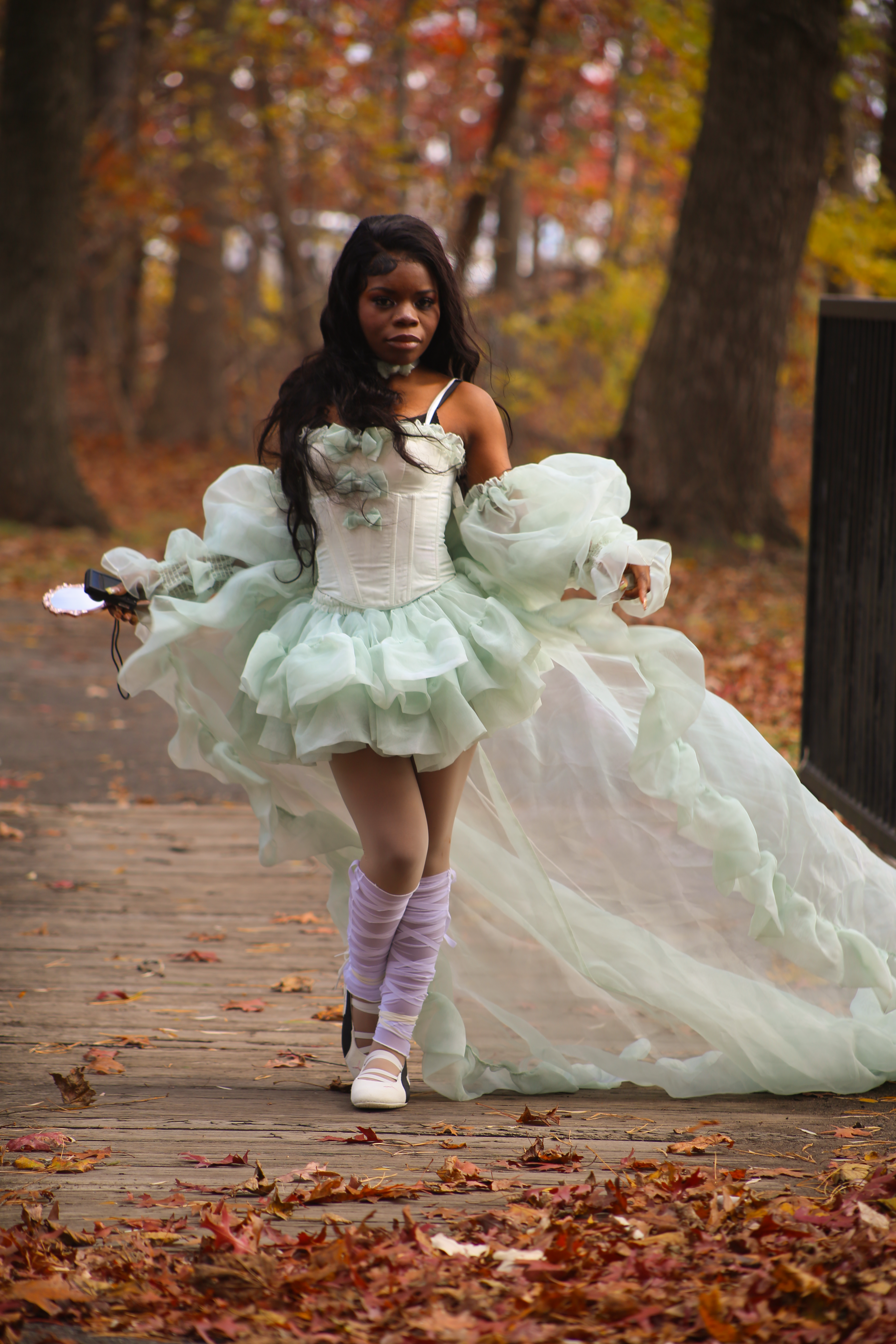 Woman in elaborate fantasy dress strolls along a leafy trail during fall in Colonie, NY.