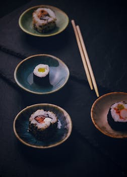 A variety of sushi rolls on ceramic plates, accompanied by chopsticks. Perfect for food lovers.