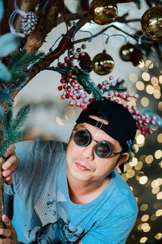 Man in glasses with Christmas decor, gold ornaments, and festive lights.