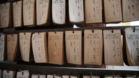 A collection of vintage library catalog cards hanging on wooden shelves, showcasing traditional Japanese text.