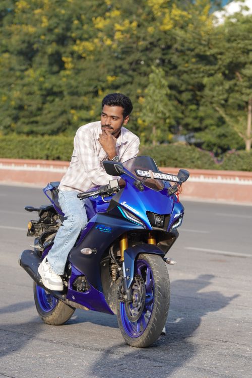 Free Man sitting on a blue motorcycle outdoors with nature in the background. Stock Photo