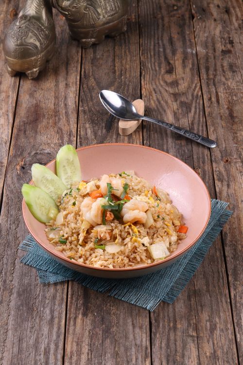 Free Tasty shrimp fried rice served with cucumber on a wooden table. Stock Photo