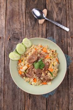 Top view of a flavorful pork fried rice dish on rustic table.