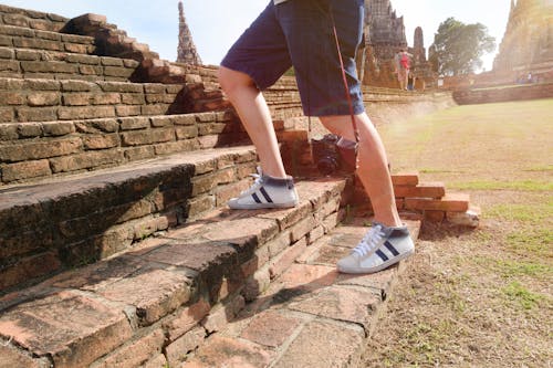 Person Wearing White-and-black Mid-rise Sneakers at Borobudur, Indonesia
