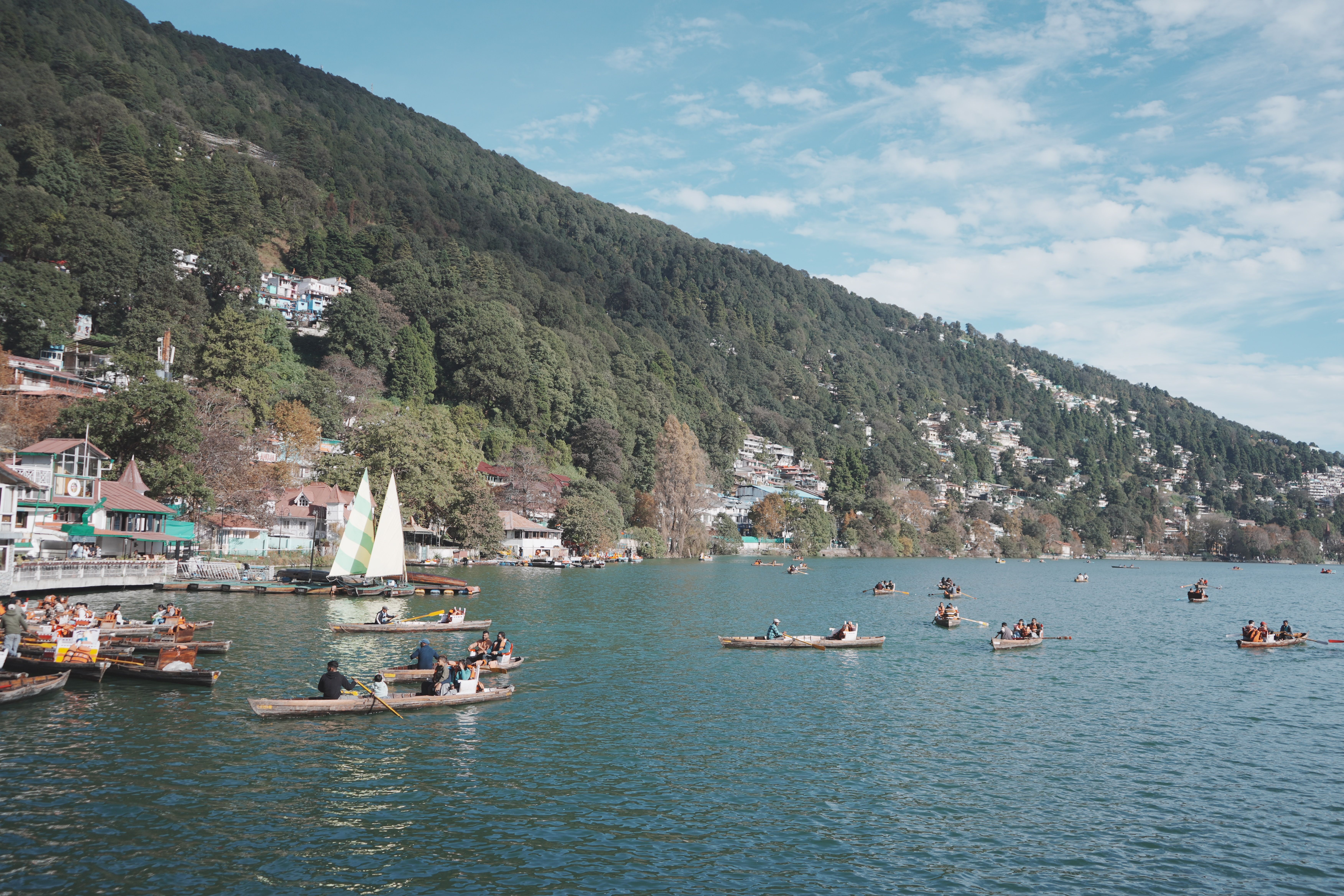 People enjoying boating on a picturesque lake surrounded by lush green mountains.