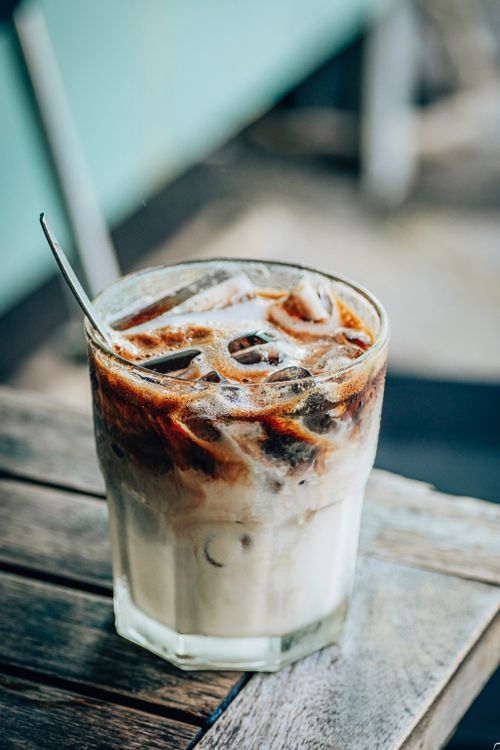 Free Close-up of a glass of iced coffee on a rustic table, perfect for summer refreshment. Stock Photo