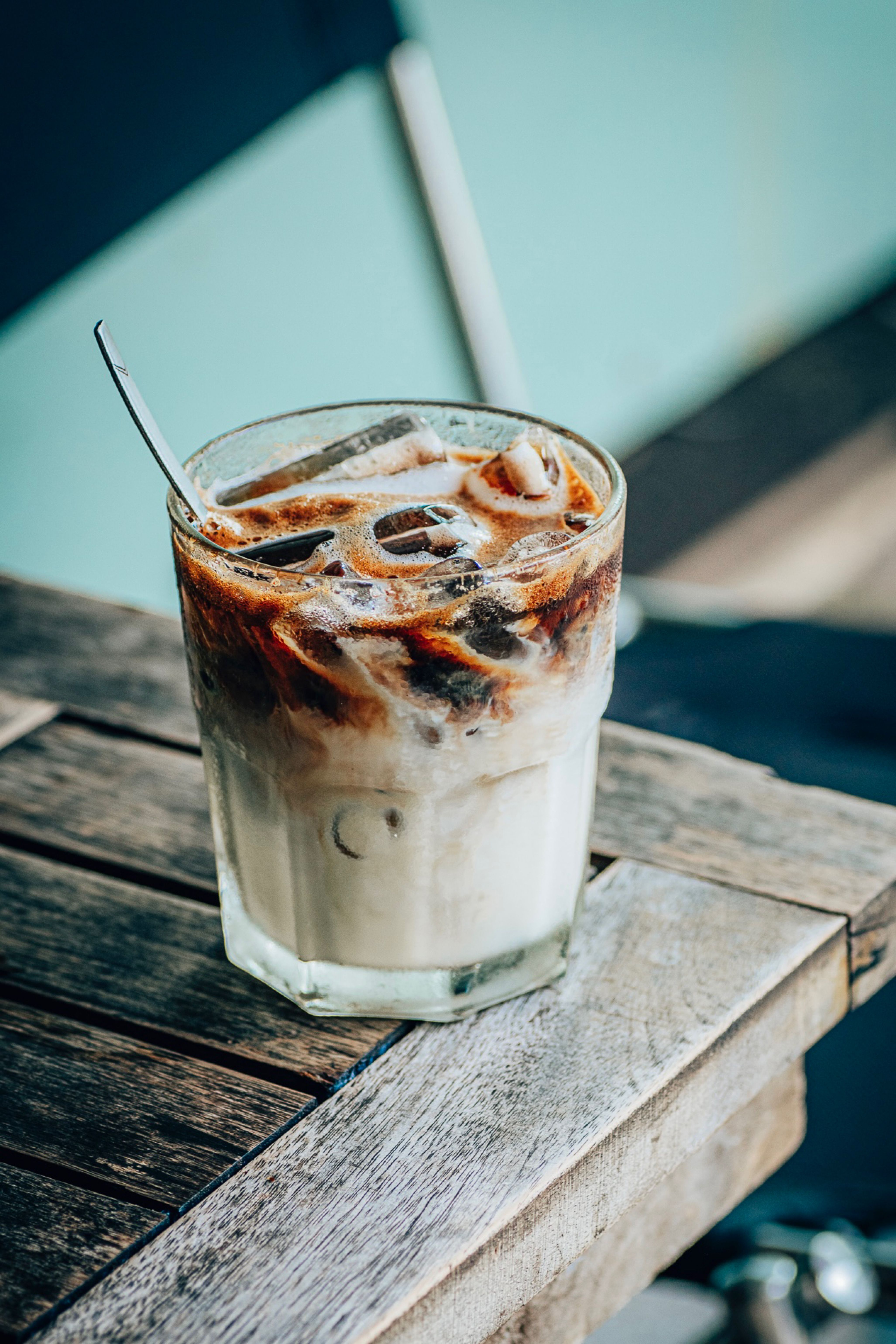A glass of iced coffee with milk on a wooden table, perfect for a summer day.