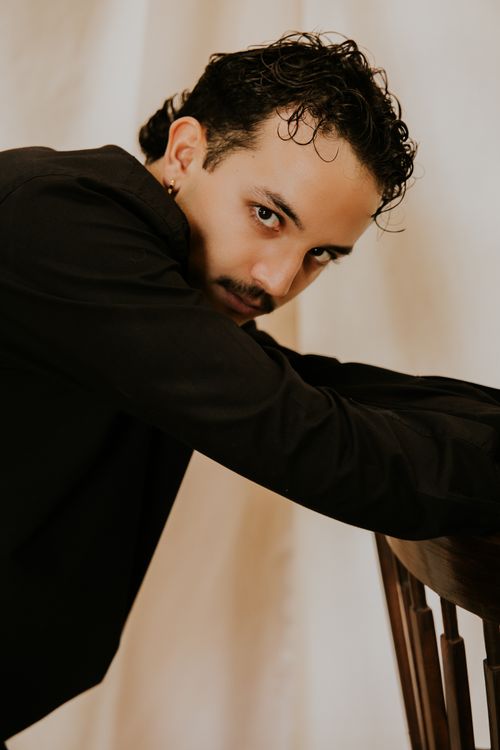Free Close-up portrait of a man in a black jacket leaning on a chair indoors. Stock Photo