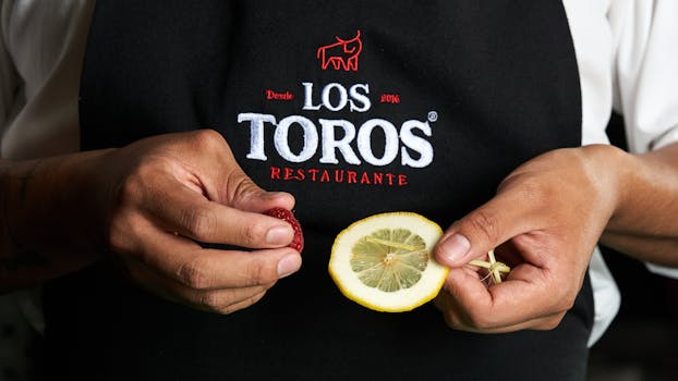 Close-up of chef holding lemon and garnish at Los Toros Restaurante.