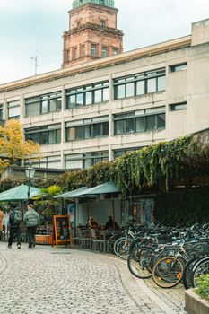 Cozy outdoor cafe with patrons in Freiburg, Germany, surrounded by bikes and lush greenery.