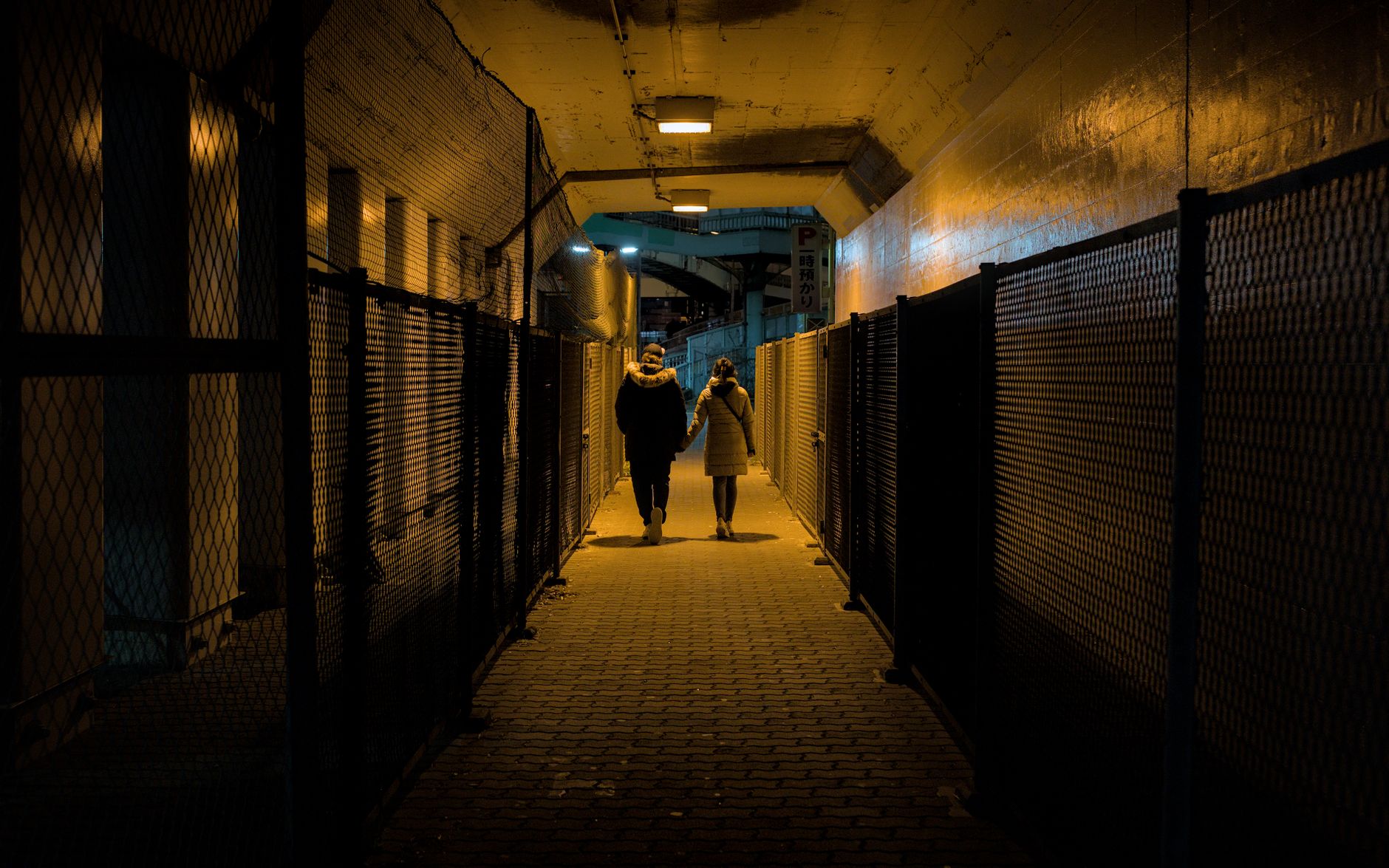 A couple walking through an illuminated underpass at night in Osaka, Japan.