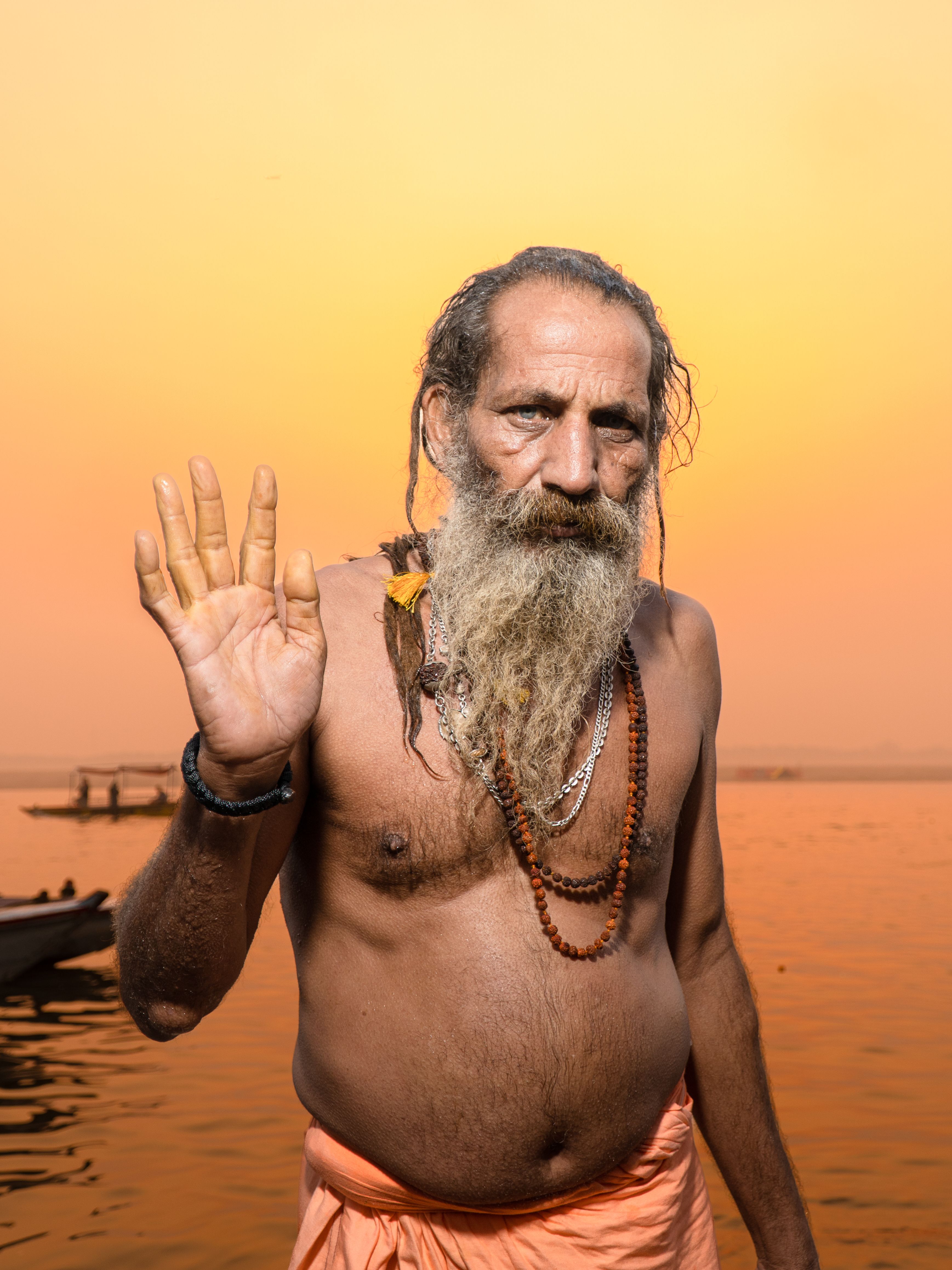 A holy man offers a blessing by the Ganges River at sunset in Varanasi, India.