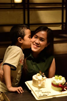 A joyful moment of a mother and son celebrating a birthday indoors with cakes.