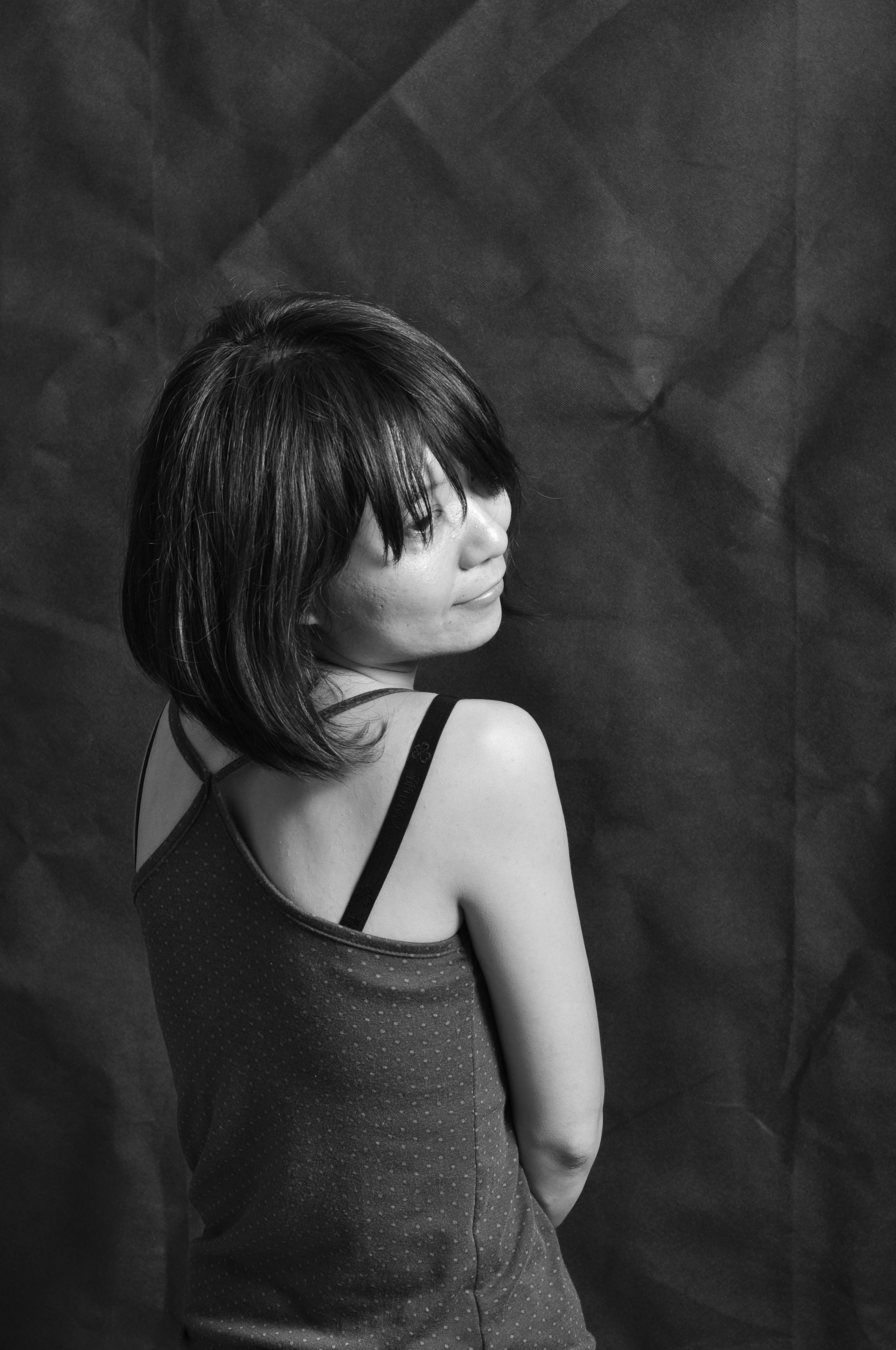 Artistic black and white portrait of a woman standing thoughtfully.