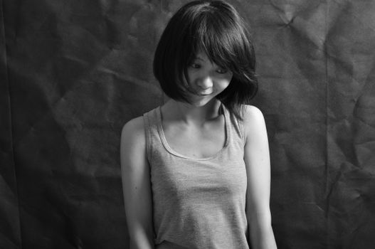 Black and white portrait of a woman with short hair looking down thoughtfully against a textured background.