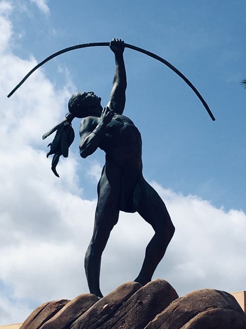 Free Dramatic view of an archer statue silhouetted against a bright cloudy sky, symbolizing strength and heritage. Stock Photo