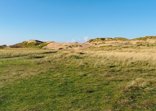 Free A tranquil landscape of sand dunes and grass at Formby Beach under a clear blue sky. Stock Photo