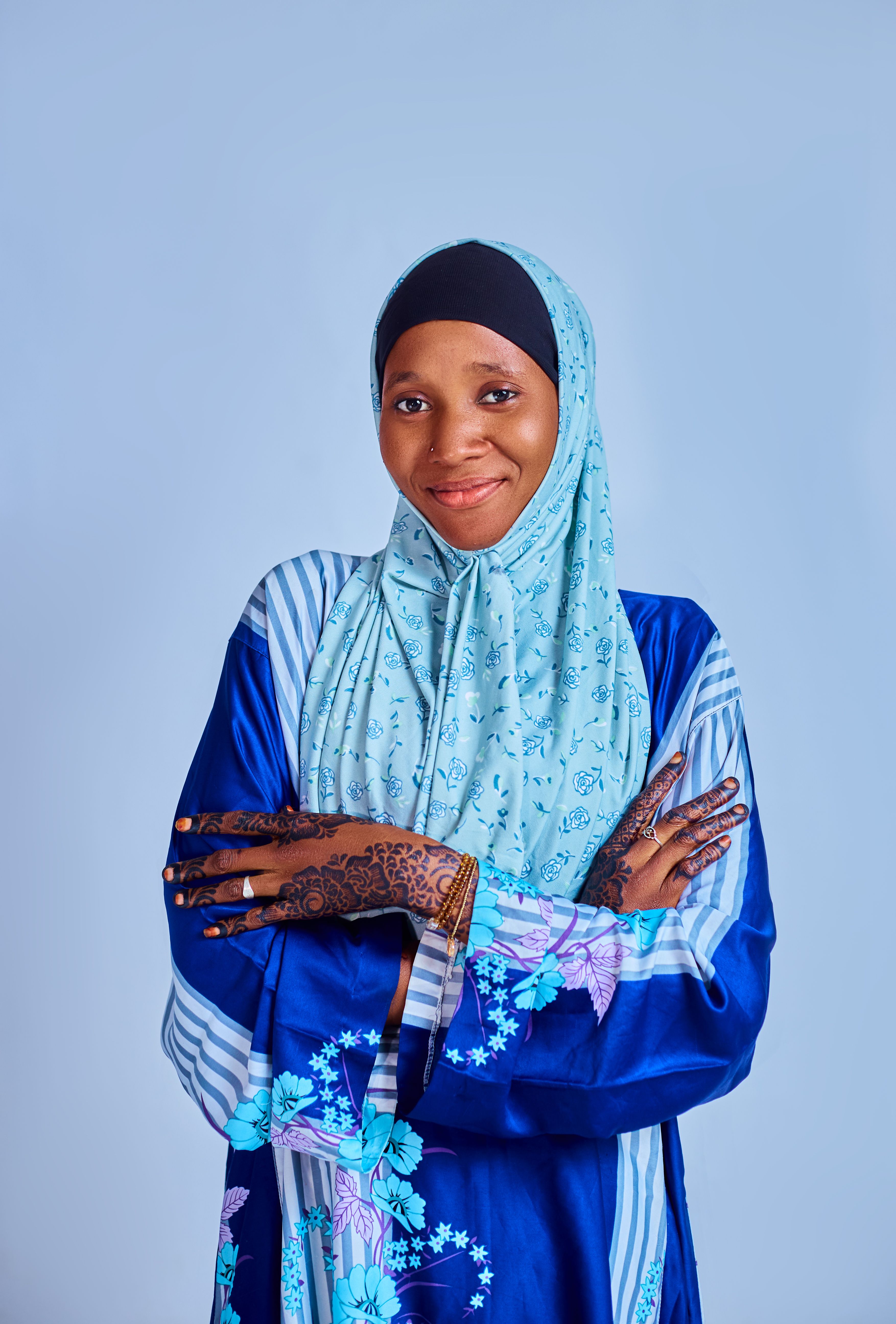 Smiling woman in blue attire with intricate henna designs. Ideal for cultural and fashion themes.