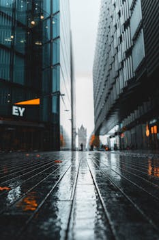 Dramatic view of a rainy street in London leading to Tower Bridge, showcasing reflections and urban architecture.