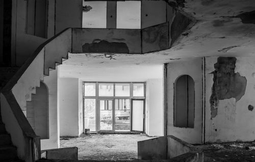 Free Black and white image of a deteriorating, abandoned building interior with stairs. Stock Photo