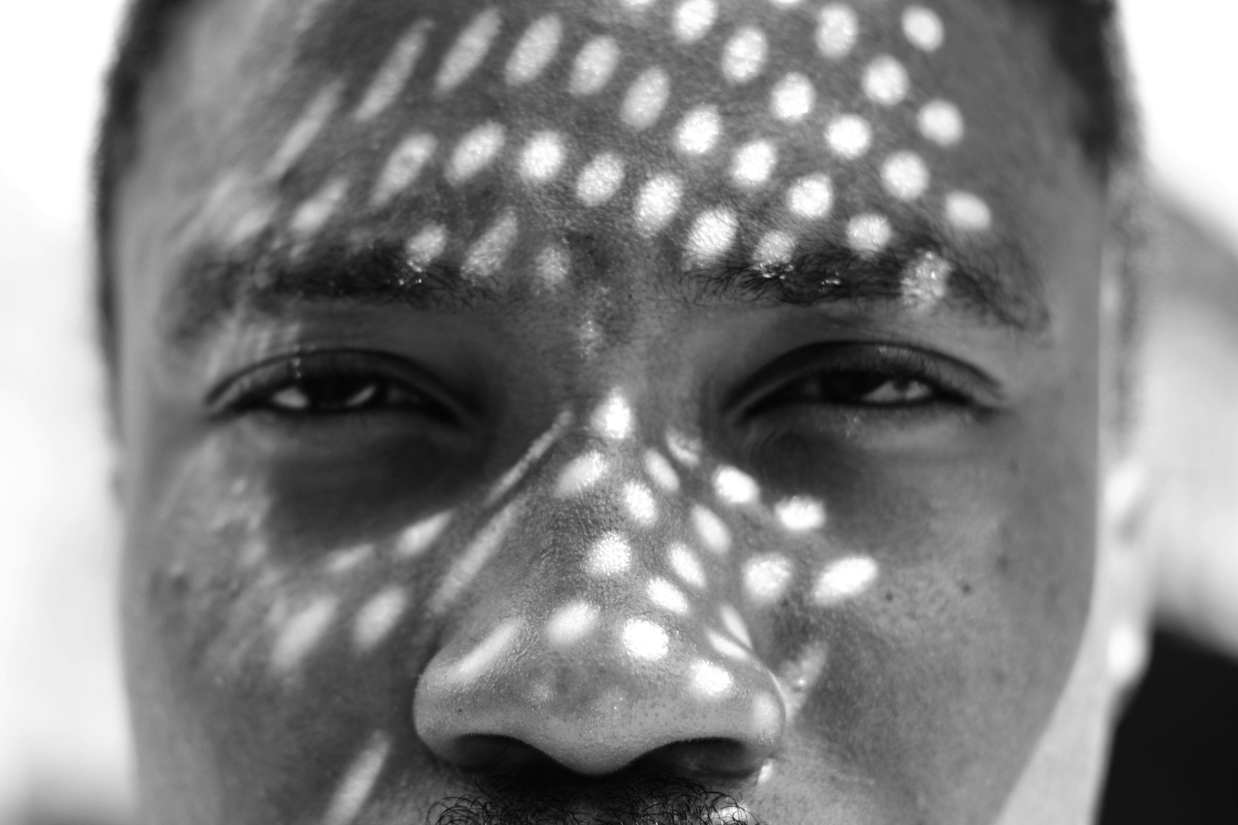 grátis Retrato em preto e branco que captura os intrincados padrões de sombra no rosto de uma pessoa em Lagos. Foto profissional