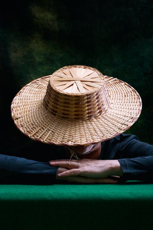 Free Woven straw hat conceals man's face against dark artistic background. Stock Photo