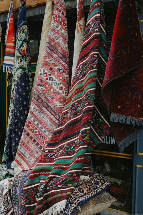 Free Vibrant woven rugs with intricate patterns hanging on a street market stall. Stock Photo