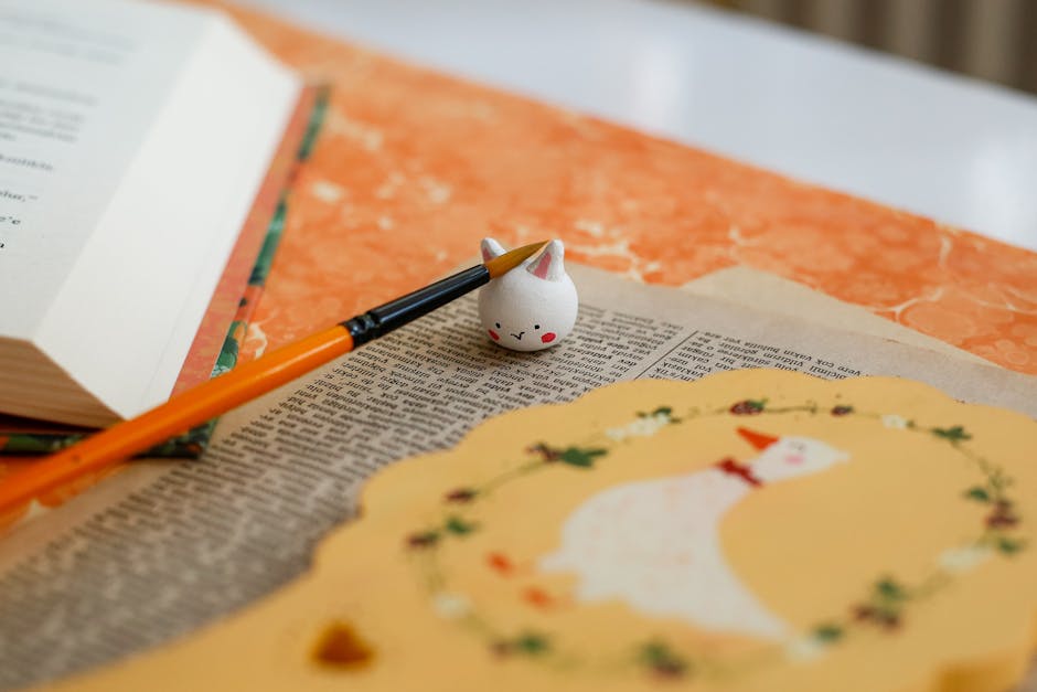Creative flat lay with open book, paintbrush, and decorative paper.