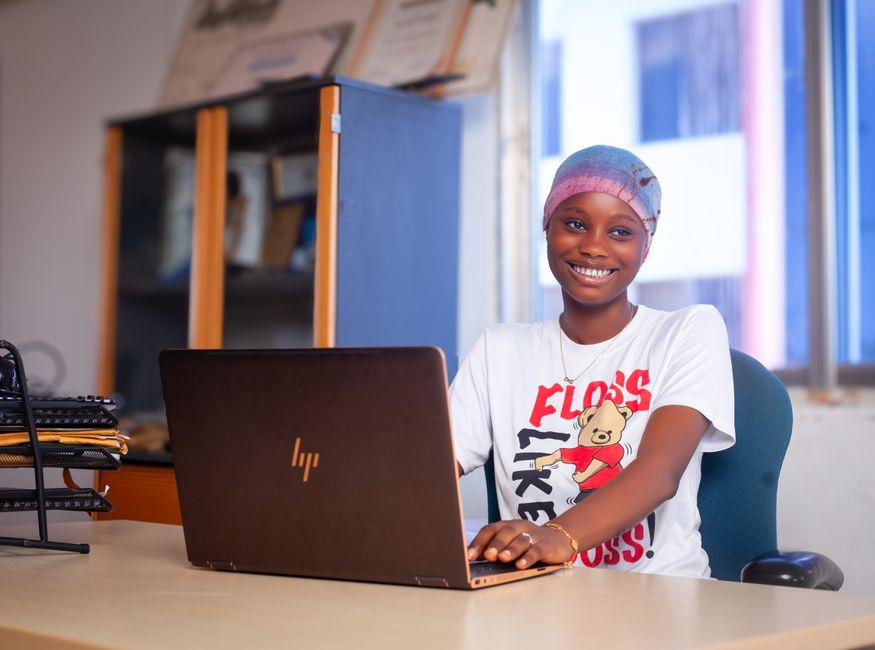 A young woman using a laptop in a cozy office, exuding positivity and focus.
