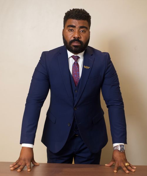 Free A confident businessman in a navy blue suit posing indoors, exuding professionalism and style. Stock Photo