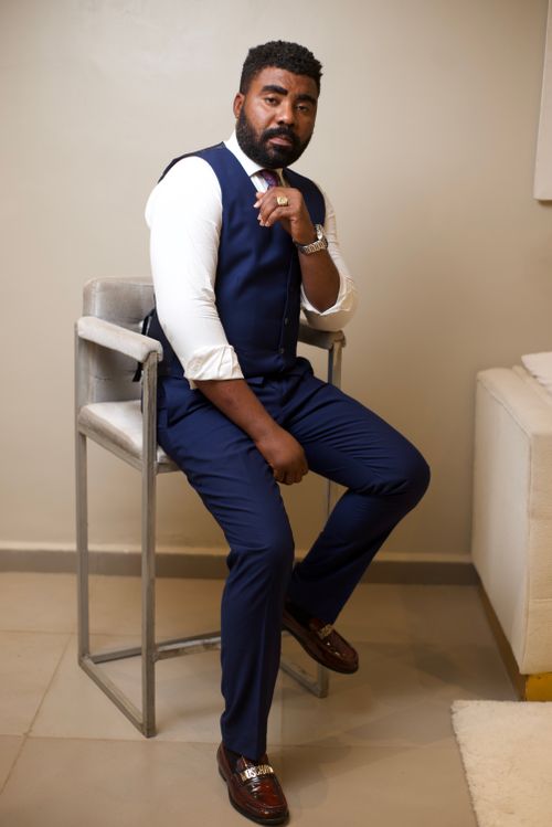 Free Elegant portrait of a confident businessman in a formal navy blue suit sitting indoors. Stock Photo