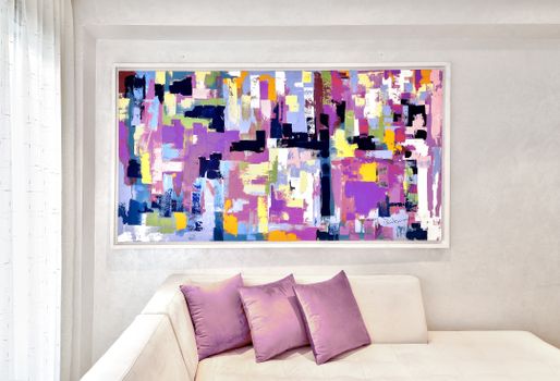 Vibrant abstract painting with bright colors above a white sofa and purple cushions.