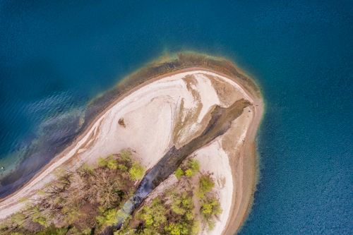 Free Aerial photograph of a small island with sandy beaches surrounded by a vivid blue lake. Stock Photo