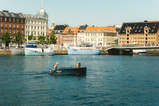Relaxing canal scene in Copenhagen with people in a rowboat enjoying a sunny day.