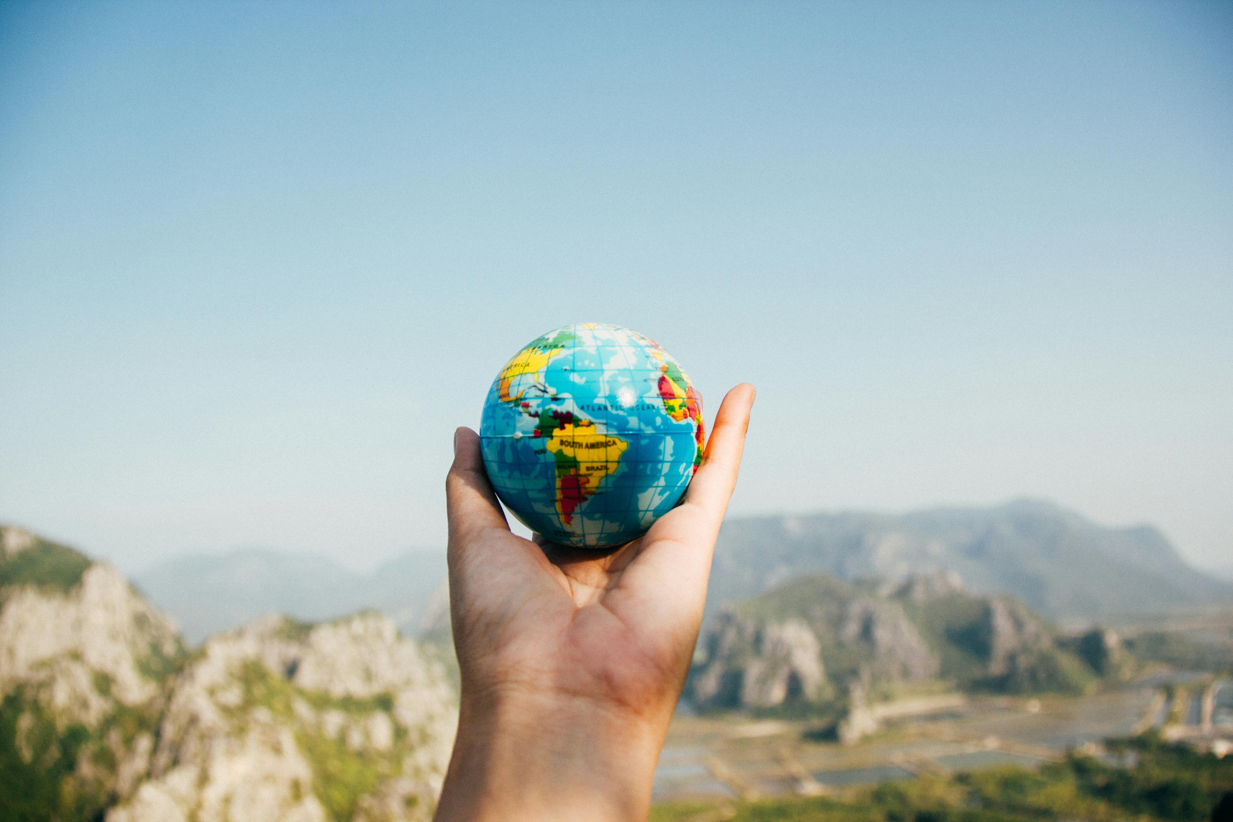 Someone holding a small globe of the world.