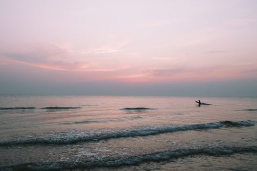 日出时分，宁静的海面上，一位孤独的冲浪者正捕捉着这份宁静