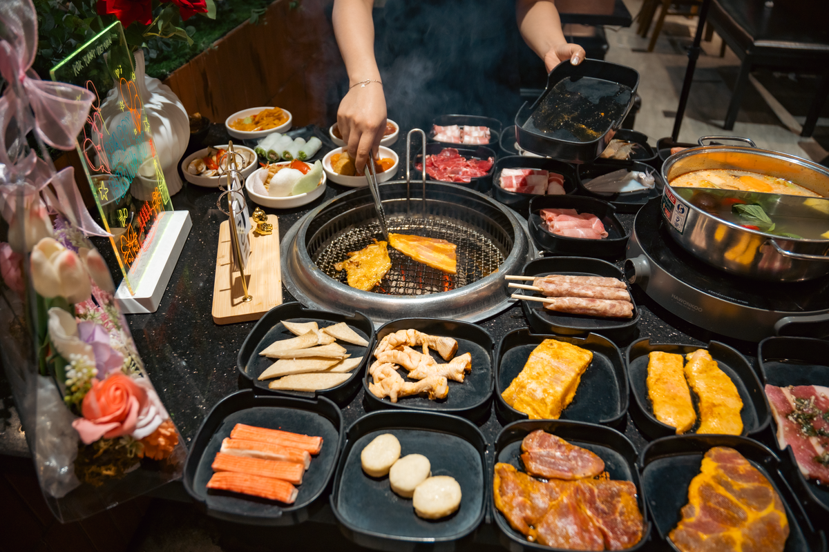 Diverse selection of Korean BBQ meats and sides on an indoor restaurant table.