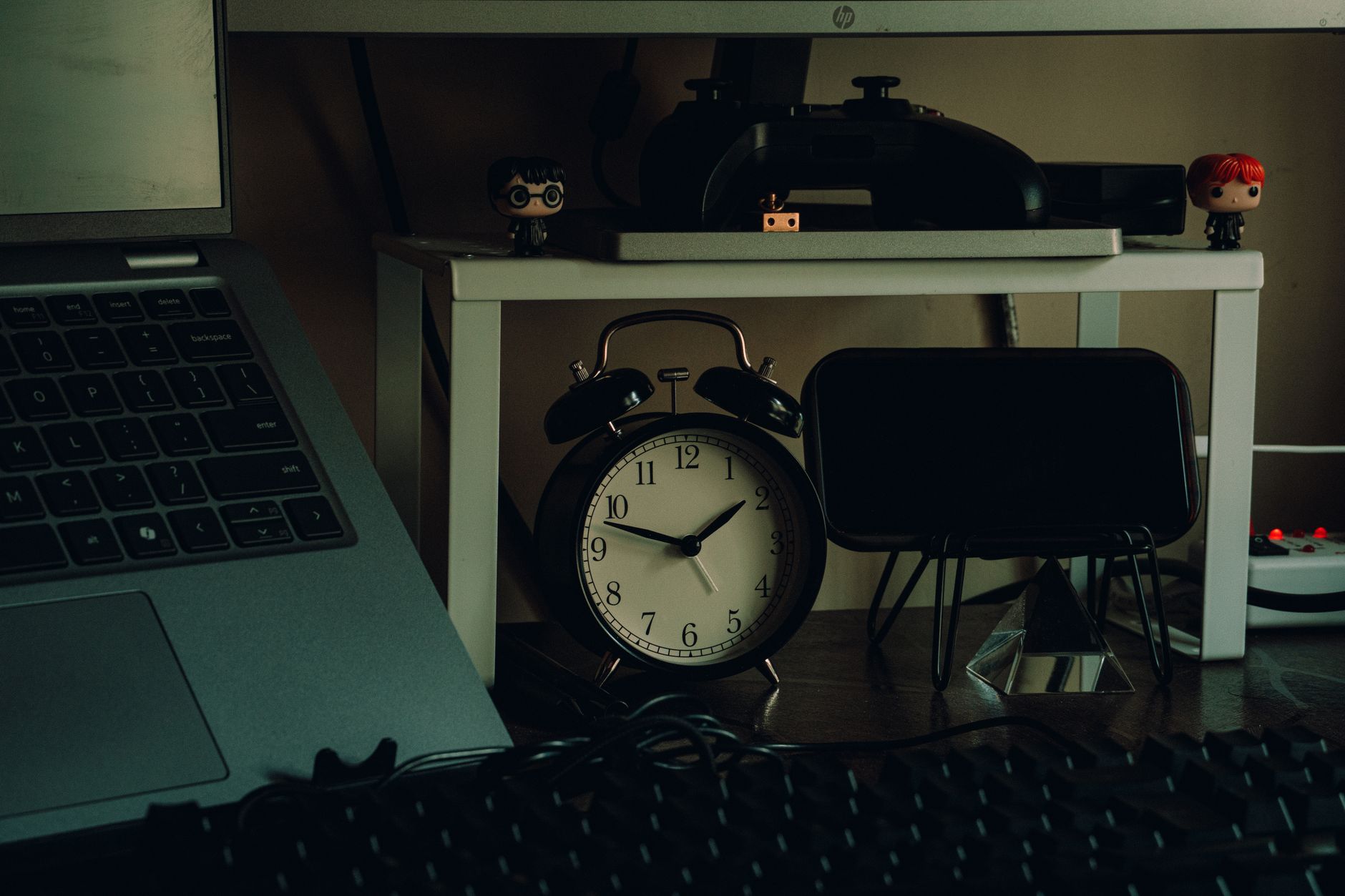 A cozy home workspace featuring an analog clock, laptop, and desk accessories for an organized work setup.